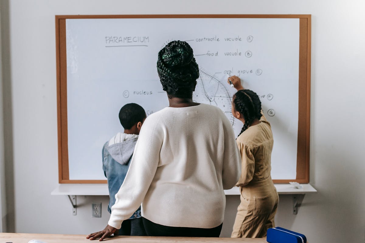 Teacher watching pupils working in a primary school classroom